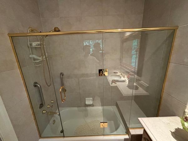 Framed glass shower door with brass trim installed in a bathroom