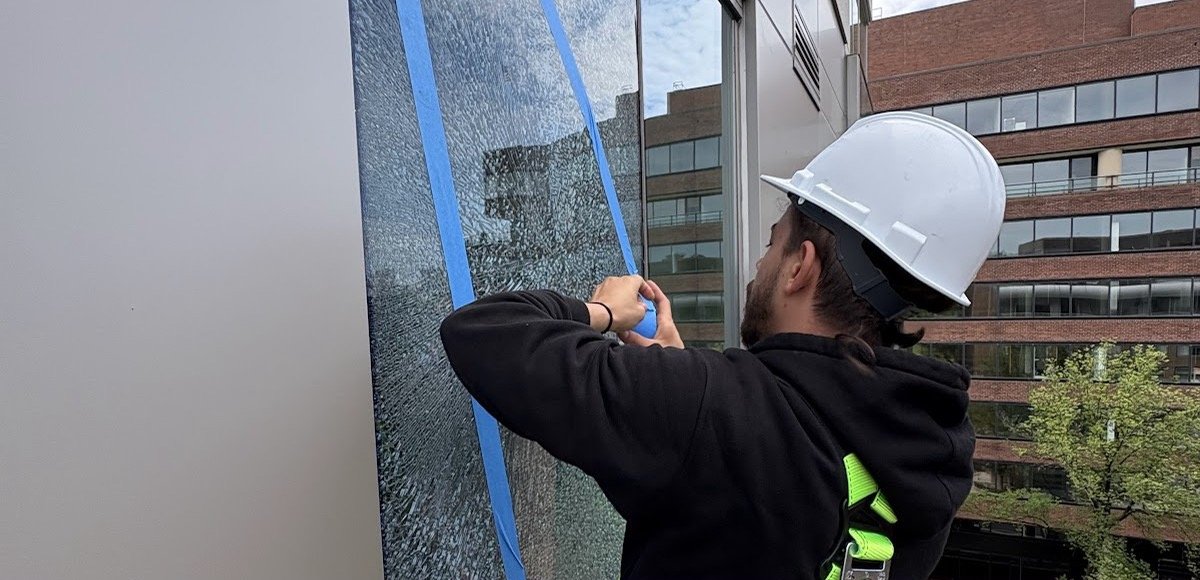 Prestine Glass technician taping a shattered office window in Washington DC before replacement