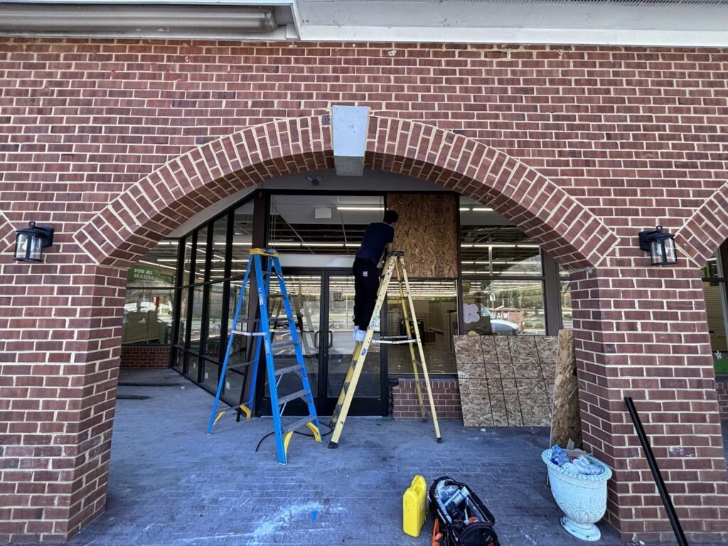 Ladders set up for storefront glass work inside a brick arch entrance