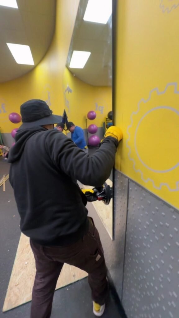 Installer fixing a glass panel in a commercial play space