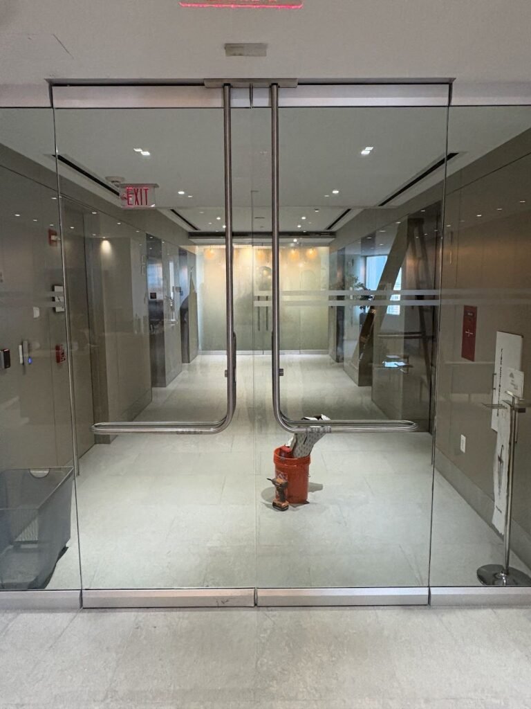 Pair of frameless glass doors with full-height glass in a building corridor