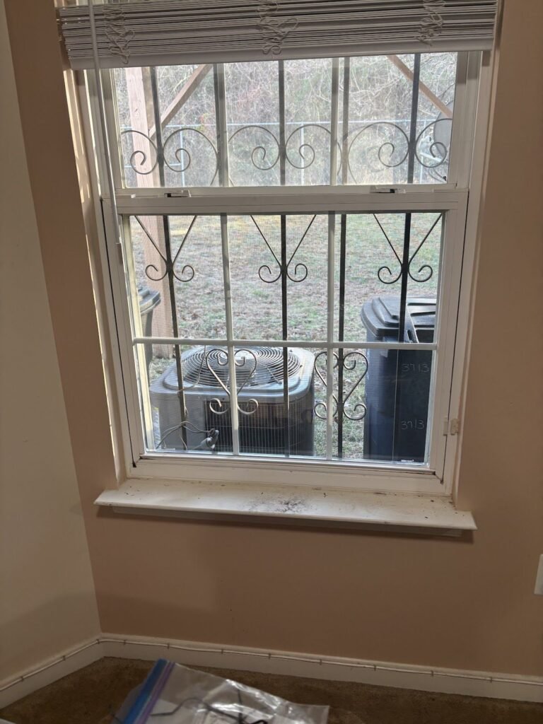 Double-hung window with new glass behind decorative security bars